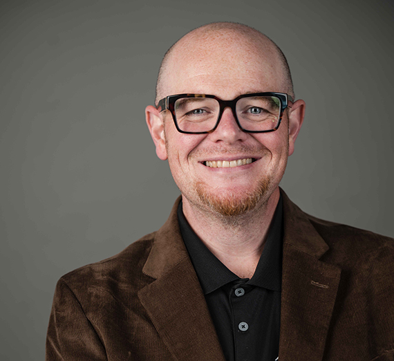 Jordy Jones posa con su computadora portátil y su hijo en su regazo.